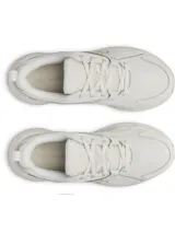 Championes Under Armour modelo W Assert 11, de color blanco y tiza, diseñados para running y entrenamiento. Presentan una capellada de malla transpirable con superposiciones de cuero resistente, mediasuela con amortiguación Charged+ Cushioning y suela exterior de goma.