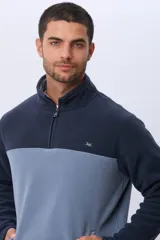 Buzo térmico de polar con diseño bicolor en azul marino y beige. Presenta cuello alto con medio cierre frontal, mangas largas y bolsillos laterales con cierre.