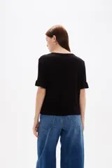 Remera negra de viscosa con textura acanalada, cuello redondo y mangas cortas terminadas en volados.