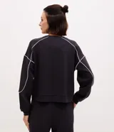 Buzo deportivo de corte oversized en color azul, con cuello redondo, manga larga y puños ajustados. Presenta detalles de frisos contrastantes en color blanco que recorren las mangas y el cuerpo de la prenda.