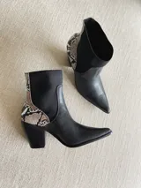 Botinetas de cuero negro con elásticos laterales y detalle de estampado reptil en el talón.