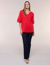 Remera blanca de silueta recta y algodón suave, con escote redondo y pequeña abertura central tipo gota. Presenta mangas de largo intermedio con aplicación horizontal de puntilla calada al tono y ruedo recto con tajos laterales.