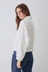Campera tipo bomber de lino y algodón, con cierre frontal y puños elásticos. Presenta un estampado integral con motivos deportivos sobre fondo blanco.