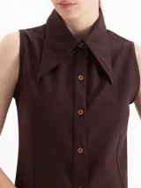 Camisa sin mangas de color marrón oscuro, confeccionada en tejido de punto, con cuello camisero clásico y cierre frontal de botones.