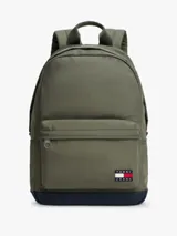 Mochila de diseño redondeado en color verde militar con base en azul marino. Cuenta con un compartimento principal con cierre de cremallera, un bolsillo frontal con cierre, asa superior y correas acolchadas ajustables. Incluye el parche distintivo de Tommy Jeans en la parte frontal.