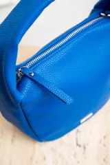 Cartera de mano color arena, con cierre superior y logo de la marca en el frente.