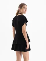 Cardigan de tejido de punto con textura acanalada, color negro, de manga corta y corte entallado. Presenta un escote en V y cierre frontal con botones decorativos de pedrería.