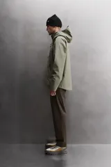 Cazadora deportiva de ajuste regular, confeccionada en tejido técnico de tres capas con membrana impermeable (resistencia al agua ≥15K) y costuras termoselladas. Presenta cuello subido con capucha ajustable, manga larga con puños ajustables con tira adherente, aberturas con cremallera termosellada en axilas para ventilación, bolsillos frontales con cremallera termofijada y bajo ajustable con elásticos laterales.