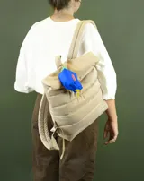 Mochila acolchada color beige con cierre superior enrollable y hebilla.