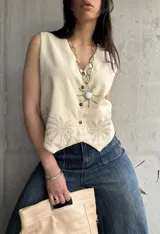 Chaleco color crema de lino liviano con bordado de palmeras en la terminación y corte recto.