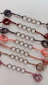 Gargantilla doble estilo choker, compuesta por dos tiras de símil gamuza que sostienen una serie de argollas metálicas plateadas entrelazadas.