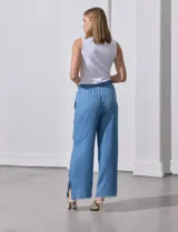 Pantalón celeste de lyocell, corte ancho, con pretina elastizada con lazo de ajuste, bolsillos verticales y ruedo desflecado.