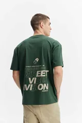 Remera oversize verde oscuro de algodón, con mangas cortas y estampa gráfica en la espalda con texto y diseño estilo pixel art.