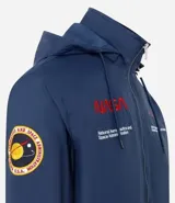 Campera rompevientos azul marino con capucha, cierre frontal y bolsillos laterales. Presenta estampado de NASA en el pecho, parche de bandera estadounidense en la manga y bolsillo utilitario en el brazo.