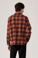 Camisa de manga larga a cuadros en tonos rojo, naranja y negro, con dos bolsillos frontales con solapa y botones blancos.