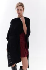 Ruana negra de tejido liviano con hilo lurex brillante, de corte amplio y caída fluida.