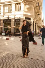 Pollera larga de lentejuelas negras con diseño de tajo lateral profundo. Presenta una cintura alta con banda lisa y corte recto que se ajusta a la silueta.