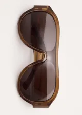 Lentes de sol tipo aviador con montura de pasta marrón traslúcida y cristales oscuros.
