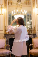 Vestido corto de lino en color rosa claro, con diseño holgado, mangas largas abullonadas con volados en contraste y cierre frontal con botones forrados.