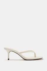 Sandalia de tacón fino medio, color blanco off-white, con diseño de tiras tipo thong para el dedo y punta cuadrada.