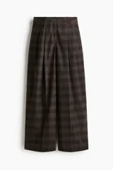 Pantalón sastrero de corte holgado y pierna ancha, con diseño a cuadros en tonos marrones. Presenta pinzas frontales, cintura estándar con cierre oculto, bolsillos laterales al bies y bolsillos traseros insertados.