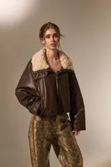 Chaqueta de cuero sintético color marrón, con cuello de piel sintética en tono crema, cierre frontal y diseño holgado.