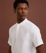 Camisa de manga corta confeccionada en mezcla de lino y algodón, con cuello tipo padre y cierre frontal parcial con botones.