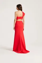 Vestido largo de fiesta color rojo, de un solo hombro, con detalle de lazo drapeado en el pecho y silueta ajustada que se ensancha levemente hacia el suelo con una sutil cola trasera.