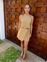 Top halter de cuero color beige, con cuello alto y ajuste mediante tiras en la espalda.