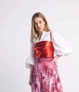 Top de cuero rojo metalizado con tirantes finos y cierre tipo corset en la espalda.