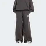 Pantalón de jogging New Balance de corte holgado y tiro alto, confeccionado en tejido de felpa suave. Presenta cintura elástica con cordón, bolsillos laterales y el logo de la marca estampado en la parte superior de la pierna.