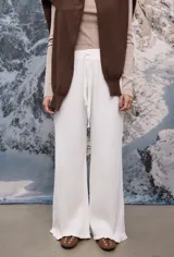 Pantalon tejido de punto en color blanco, de corte recto y holgado, con cintura elástica y cordón ajustable. Presenta una textura acanalada y terminación con volados sutiles en la botamanga.