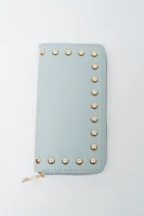 Billetera negra con cierre perimetral y tachas doradas decorativas en el borde frontal.