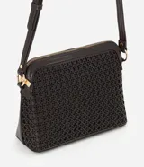 Bolso bandolera Satinato en color marrón oscuro, de diseño compacto y estructurado, confeccionado en poliuretano (PU) texturizado. Presenta trama calada en la parte frontal, cierre superior con cremallera metálica dorada y correa larga ajustable para llevar cruzada.