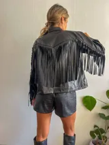Campera negra de cuero sintético con cierre frontal, cuello clásico y flecos en las mangas.
