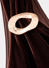 Mono largo de fiesta confeccionado en terciopelo color marrón chocolate. Presenta un diseño asimétrico con un solo hombro, detalle metálico en el tirante, fruncido lateral en la cintura y pantalón de corte recto y fluido.