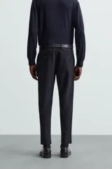 Pantalón chino de corte slim fit, confeccionado en tejido elástico. Presenta bolsillos frontales, bolsillos traseros de vivo con botón y cierre frontal con cremallera y botón.