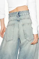 Jeans de mezclilla de tiro medio con diseño amplio tipo balloon, costuras marcadas y bajo con puño elástico. Cuenta con bolsillos delanteros y traseros, y cierre frontal con cremallera y botón metálico.