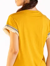 Remera color naranja de manga corta, confeccionada en algodón, con detalles de flecos y bordado en las mangas.