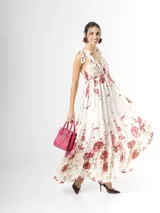 Vestido largo confeccionado en mezcla de tencel y lino, con fondo off white y estampado floral en tonos rosados, rojos y verdes. Cuenta con escote en V pronunciado, breteles anchos ajustables con lazos en los hombros, corte bajo el busto y falda amplia con volados escalonados.