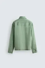 Camisa de corte relajado confeccionada en tejido fluido con mezcla de lyocell. Presenta diseño de rayas verticales, cuello solapa, manga larga con puños abotonados, bolsillos de plastrón con solapa en el pecho y cierre frontal con botones a presión.