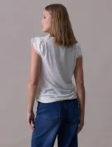 Remera blanca de modal, marca French Laundry, con escote en V. Presenta apliques de puntilla en las mangas y el escote, y un detalle fruncido en los hombros.