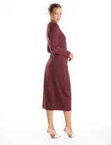 Vestido midi de seda fría color bordó, con cuello a la base, mangas largas y detalle de lazo ajustable en la cintura que crea un efecto drapeado lateral.