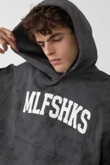 Hoodie de corte oversize con efecto de lavado desgastado en color gris oscuro. Presenta capucha amplia, bolsillo tipo canguro frontal y estampado tipográfico en blanco en el pecho.