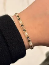 Pulsera artesanal confeccionada con cuentas miyuki en tonos beige, blanco, negro y detalles metálicos.