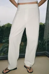 Pantalón de tiro medio confeccionado en una mezcla de lino y algodón. Presenta un diseño de corte recto con trabillas en la cintura, bolsillos laterales y cierre frontal con cremallera, botón y ganchos metálicos.