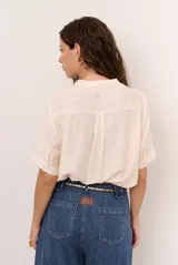 Camisa de manga corta color blanco con cuello mao y cierre frontal de botones. Presenta detalles bordados tono sobre tono en el canesú y diseño de corte recto.