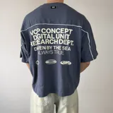 Remera gris oscuro de corte boxy y mangas cortas, con un gran estampado frontal en el pecho que dice "CONCEPT" en líneas blancas.