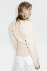 Remera de punto fino suave color beige con escote en V, modelo de cintura entallada con mangas dolman largas.