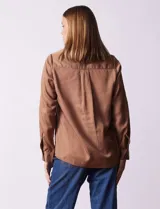 Camisa color verde oliva de lyocell, marca Cyrus. Tiene cuello con solapa, abertura central con botones, mangas 3/4 regulables con presilla y botón, y dos bolsillos delanteros aplicados.